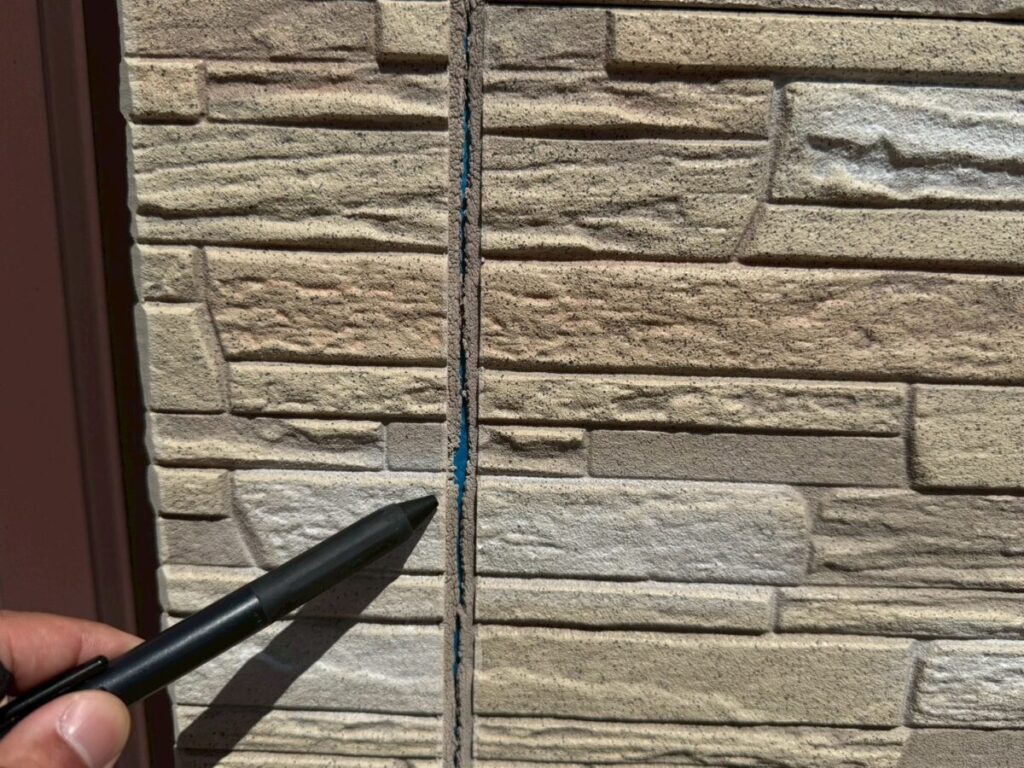 外壁の隙間と劣化したコーキングを確認している様子｜補修が必要な状態