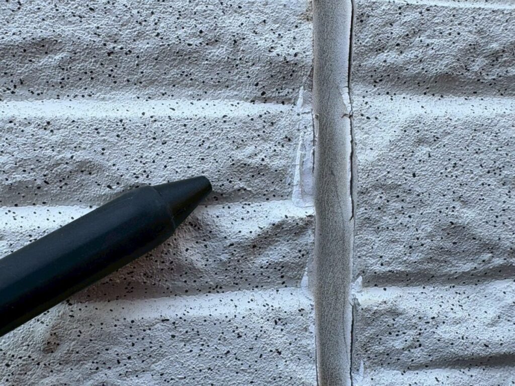 外壁のコーキングのひび割れを指で示している状態